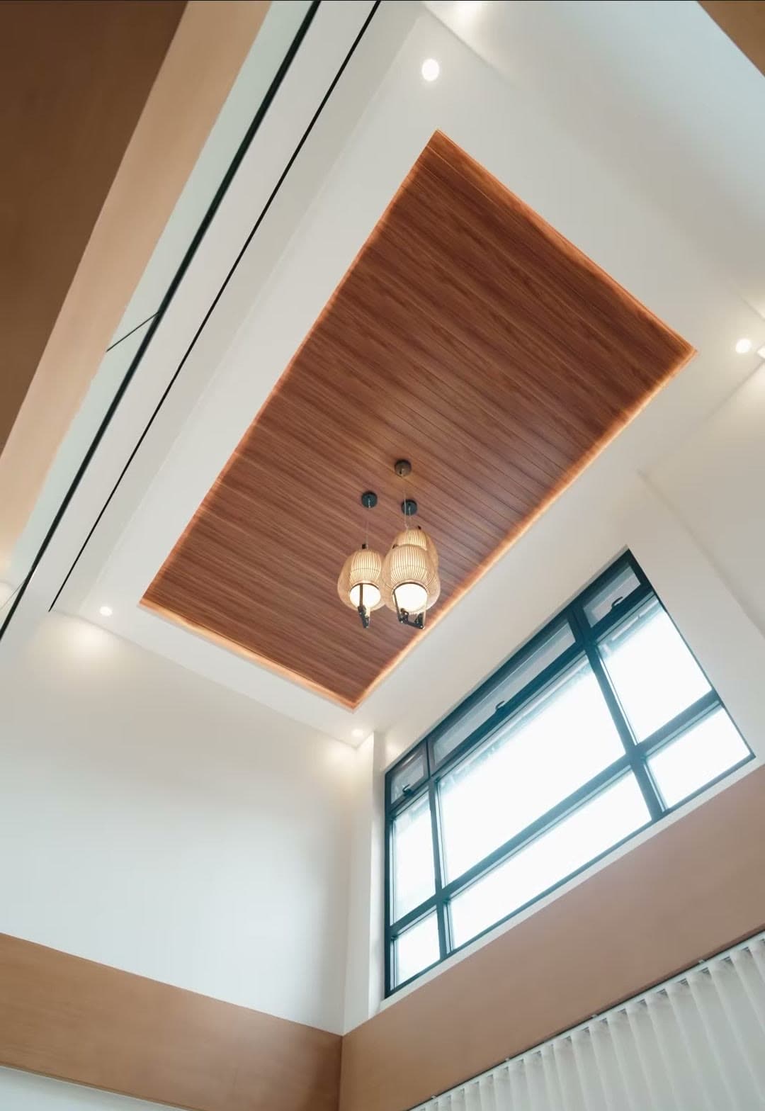 Double-height ceiling with a wood-lined panel and high windows