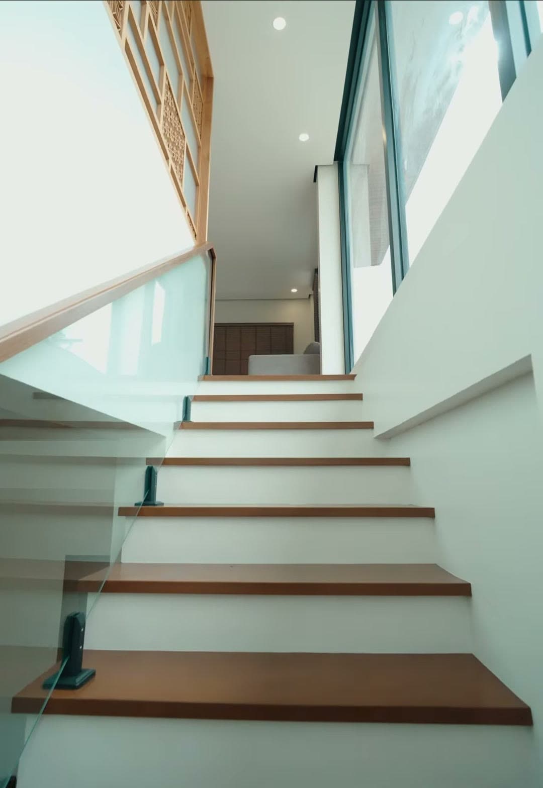 Floating timber stairs lit by tall windows